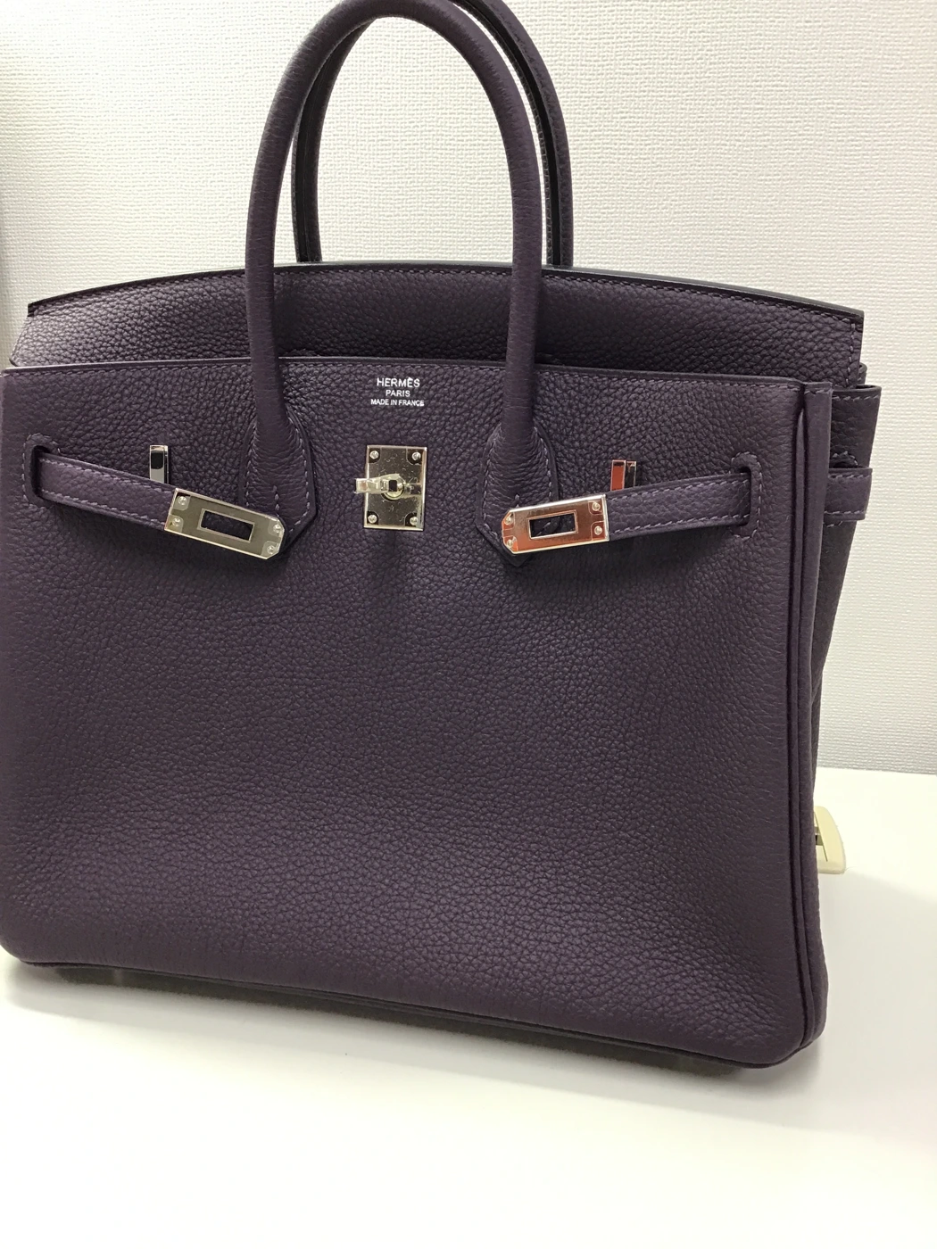 Intake photograph of a purple leather handbag, with numbered markers on its shape, leather surface and clasp